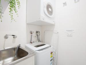 Una pequeña cocina con fregadero y lavadora. en Bay Parklands, 68 2 Gowrie Ave - Fully ducted aircon, wifi, pool, tennis court, communal spa, en Shoal Bay 18 fotos más