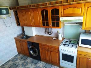 a kitchen with wooden cabinets and a washing machine at Ильинская 3к посуточно почасово in Sumy