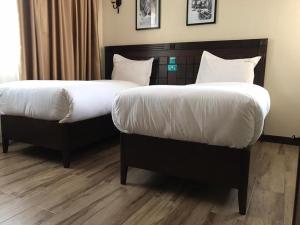duas camas com cobertores brancos e almofadas num quarto em Hemak Suites em Nairobi