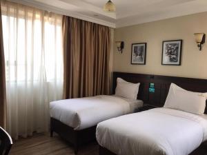 um quarto de hotel com duas camas e uma janela em Hemak Suites em Nairobi