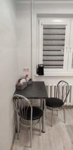 mesa de comedor con 2 sillas y ventana en Butas miesto centre/ Apartment in the city center, en Šiauliai
