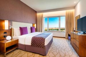 a bedroom with a bed and a flat screen tv at Crowne Plaza Muscat OCEC, an IHG Hotel in Muscat