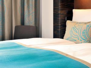 a bedroom with a bed with blue and white sheets at Motel One Bremen in Bremen