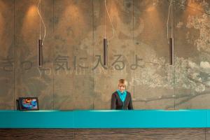 a woman is standing in front of a mirror at Motel One Düsseldorf Hauptbahnhof in Düsseldorf