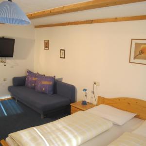 a bedroom with a bed and a couch at Pension Wirt am Bach in Terento