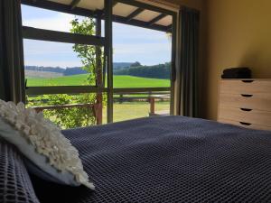 a bedroom with a bed and a large window at Fairway Cottage in Oamaru