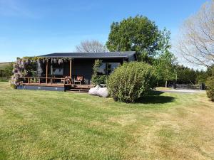 una casa nera con un giardino davanti di Fairway Cottage a Oamaru