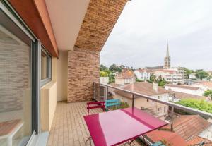 a balcony with a pink table and a view of a city at Appartement à Arcachon à 3 min à pied de la plage in Arcachon