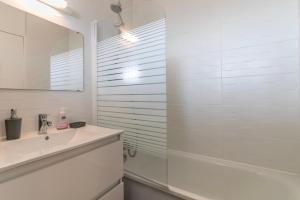 a white bathroom with a sink and a shower at Appartement à Arcachon à 3 min à pied de la plage in Arcachon