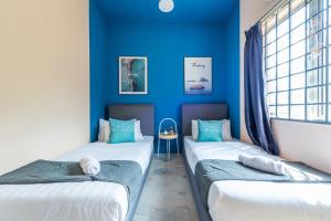 - 2 lits dans une chambre aux murs bleus dans l'établissement 3BR Retreat Homestay near to GoldCoast, Sepang by Verano, à Sungai Pelik