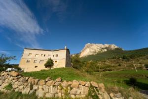 um edifício numa colina com uma montanha ao fundo em HOSTAL RURAL CAL XIC Saldes em Saldés