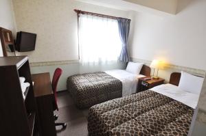 a hotel room with two beds and a window at Futsukaichi Green Hotel in Chikushino