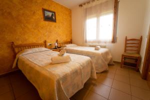 a bedroom with two beds and a window and a chair at HOSTAL RURAL CAL XIC Saldes in Saldés