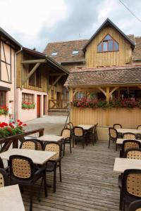 um pátio exterior com mesas e cadeiras e um edifício em La Griffe à Foin au Restaurant raisin D'or em Mittelbergheim