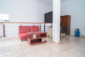 a living room with a red chair and a tv at KoolKost @ Harapan Jaya Bekasi in Bekasi