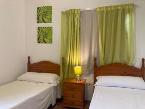 a bedroom with two beds and a lamp on a night stand at Pensión Amparo Las Hayas in Valle Gran Rey