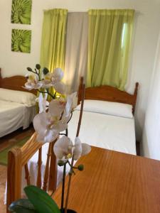 una habitación con 2 camas y una mesa con flores en Pensión Amparo Las Hayas en Valle Gran Rey