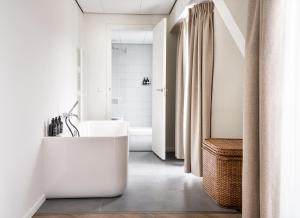 La salle de bains est pourvue d'une baignoire blanche et d'un lavabo. dans l'établissement Park Centraal Den Haag, part of Sircle Collection, à La Haye