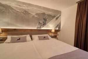 a bedroom with a bed with a painting on the wall at Matterhorngruss Apartments in Zermatt