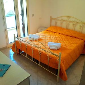 ein Bett mit einer orangefarbenen Bettdecke in einem Zimmer in der Unterkunft Case Vacanza IonianTravel Gallipoli in Gallipoli