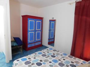 a bedroom with a bed and two blue windows at Case Vacanza Elisir in Favignana