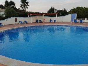 a large blue swimming pool with chairs and a gazebo at Komfortables Town House in traumhafter Lage in Budens