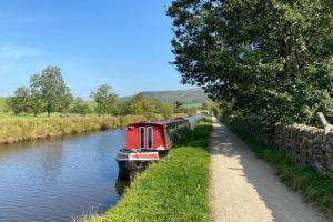 ein rotes Boot auf einem Fluss neben einem Pfad in der Unterkunft Bailey Cottage in Gargrave