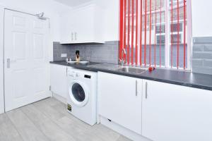 een witte keuken met een wasmachine en een wastafel bij Townhouse @ 543 London Road Stoke in Trent Vale