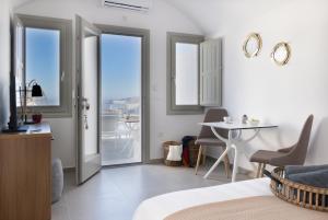 a bedroom with a bed and a table and a balcony at Symphony Suites Santorini in Pyrgos