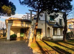 een groot wit huis met een boom ervoor bij Villa Alda Suites & Rooms in Cervia