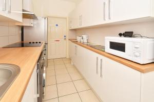 a kitchen with white cabinets and a white microwave at Townhouse @ 178 Ruskin Road Crewe in Crewe