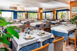 una sala da pranzo con tavoli, sedie e finestre di Hotel Palace a Bibione