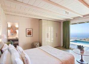 a bedroom with a large bed and a large window at Aeolis Tinos Suites in Tinos