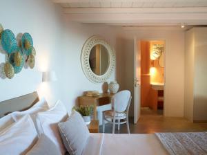 a bedroom with a bed and a table and a mirror at Aeolis Tinos Suites in Tinos