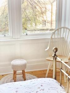 Dieses weiße Zimmer verfügt über einen Stuhl und ein Fenster. in der Unterkunft Oakshaw Apartment in Paisley