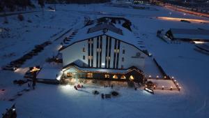 a large building with lights in the snow at night at Sarikamis Habitat Hotel in Sarıkamıs