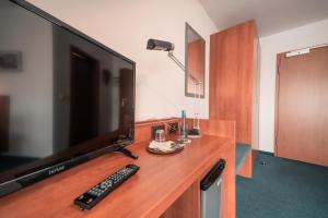 einen TV auf einem hölzernen Schreibtisch mit Fernbedienung in der Unterkunft Airport Lounge Hotel Düsseldorf in Düsseldorf + 15 Fotos