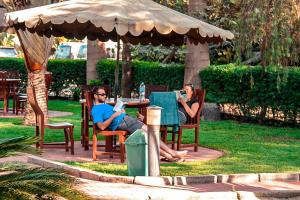 due persone sedute a un tavolo sotto un ombrello di New Charity Hotel International ad Arusha