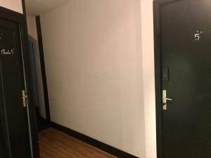 - un couloir avec deux portes noires et du parquet dans l'établissement Mamie Jane co-munity, à Aix-les-Bains