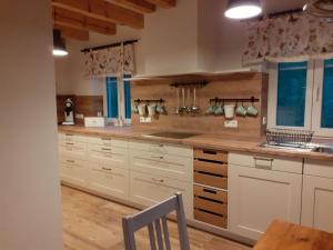 uma grande cozinha com armários brancos e piso em madeira em Villa Pauline em Baiersbronn