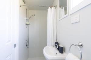 a white bathroom with a shower and a sink at The Saddle Camp Tiny House, Braidwood in Braidwood