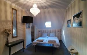 a bedroom with a bed and a chandelier at Lika Panzió Gyula in Gyula