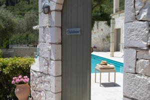 a door to a house with a pool and a table at Fiscardo View Villas in Fiskardo