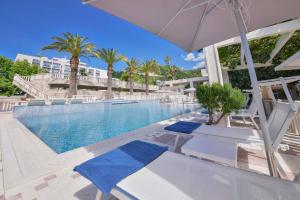 a pool at a resort with two chairs and an umbrella at Mediteran Hotel & Resort in Budva