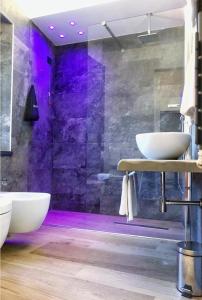 un bagno con 2 lavandini e una doccia con illuminazione viola di Arenarius Home Resort & SPA a Torricella in Sabina