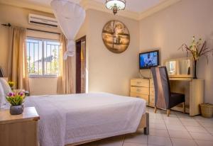 a bedroom with a bed and a chair and a television at Seaview Gardens Hotel in Kololi