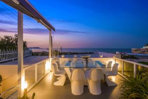 uma varanda com uma mesa e cadeiras à noite em White Luxury Villa em Hersonissos