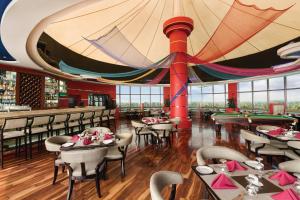 restauracja ze stołami i krzesłami oraz dużym sufitem w obiekcie Ramada by Wyndham Alleppey w mieście Alappuzha