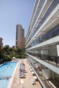 ein großes Gebäude mit einem Pool neben einem Strand in der Unterkunft Hotel Perla in Benidorm