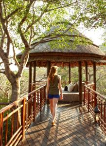 uma mulher a andar numa ponte com um gazebo em Thanda Safari em Hluhluwe